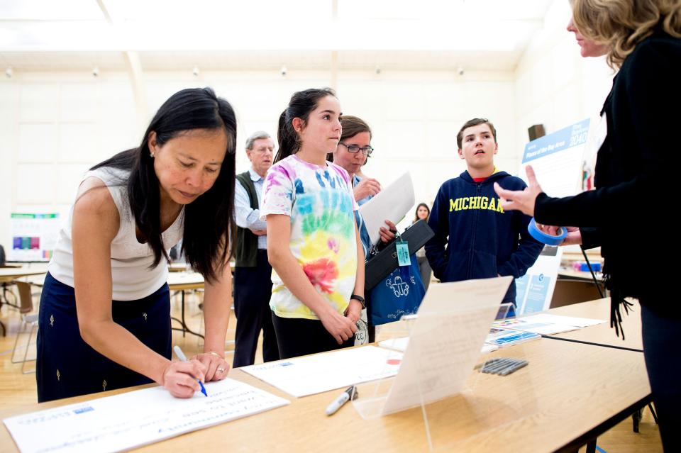 A woman writes down information while two children speak to staff at a Plan Bay Area 2040 open house in Burlingame in 2016.