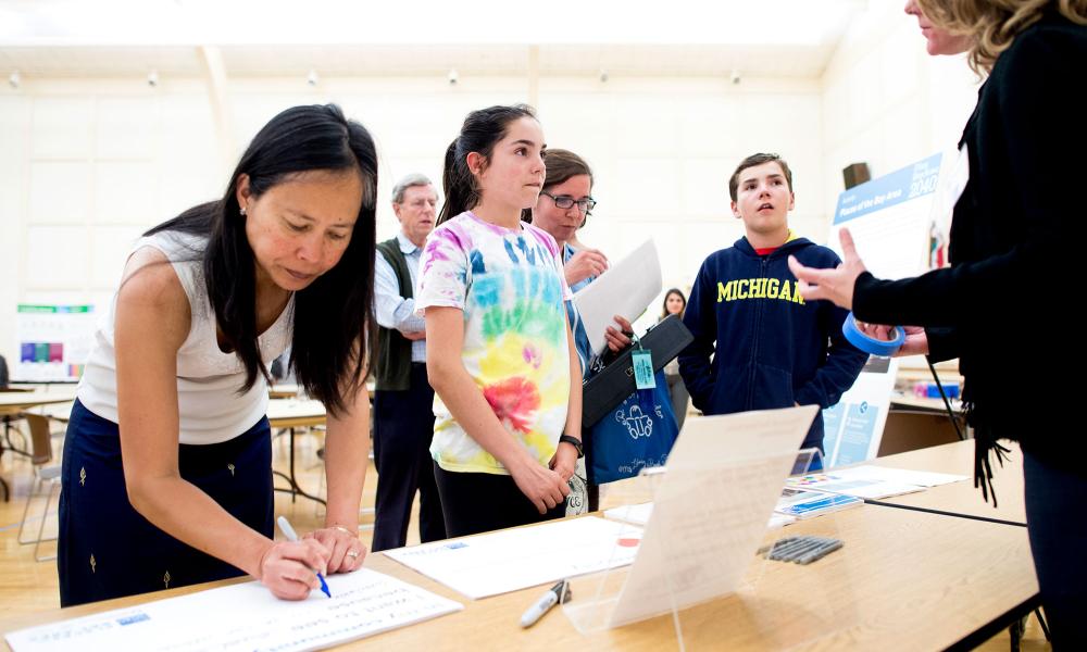 A woman fills out a comment form while children discuss Plan Bay Area 2040 with staff at the Spring 2016 San Mateo County open house in Burlingame. 