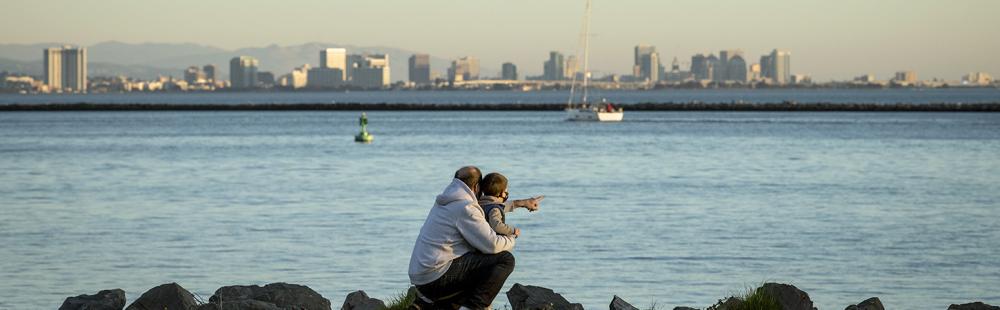 An adult and child pointing at the water in Richmond, California.