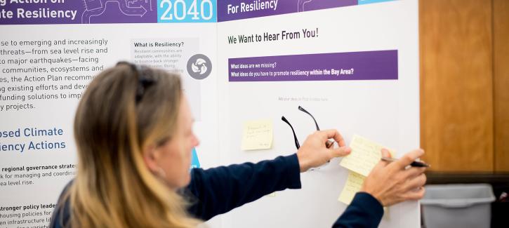 A woman posts a comment note to the resiliency display board at the Plan Bay Area 2040 open house in Napa.