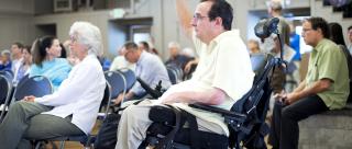 A man in a wheelchair raises his hand to ask a question at the Plan Bay Area 2040 open house in Marin County in 2016.